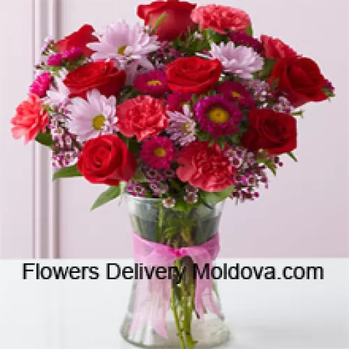 Roses rouges, œillets rouges et autres fleurs assorties arrangées magnifiquement dans un vase en verre