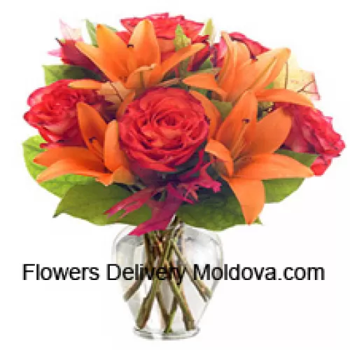 Des lis orange et des roses orange avec des remplissages saisonniers disposés magnifiquement dans un vase en verre