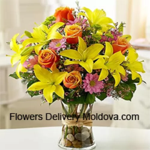 Lys jaunes, roses oranges et gerberas roses avec des remplissages saisonniers dans un vase en verre