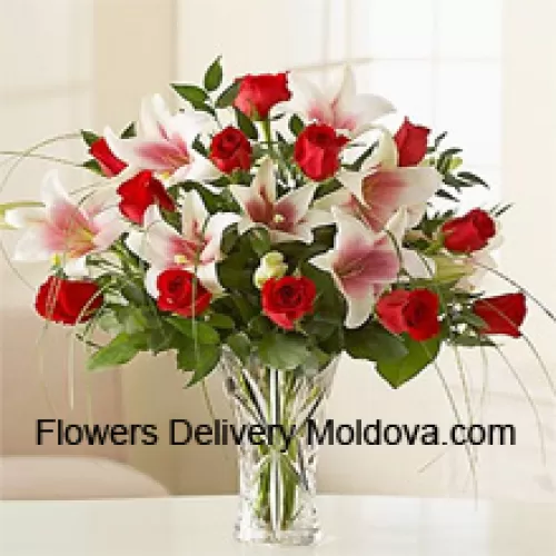 Roses rouges et lys roses avec des remplisseurs saisonniers dans un vase en verre